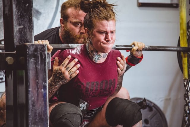 Woman in a deep squat position, confidently lifting a heavy barbell, epitomizing Strength Training' in action