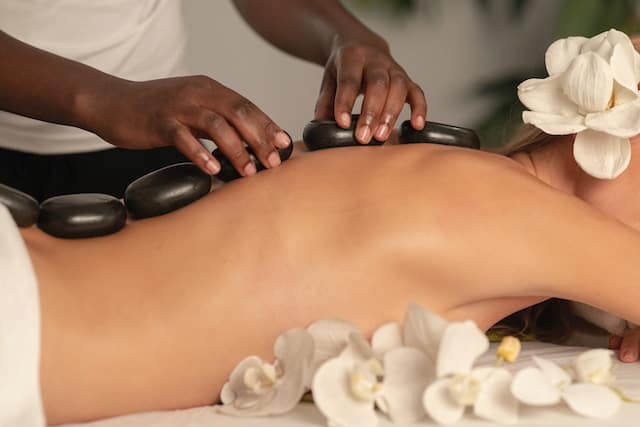 Woman relaxing during a hot stone massage treatment, capturing the importance of Rest, Recovery, and Rejuvenation in overall wellness