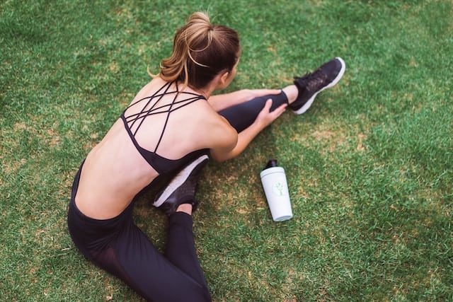 Woman sitting down and stretching her muscles, embodying the importance of Perfecting the Warm-Up