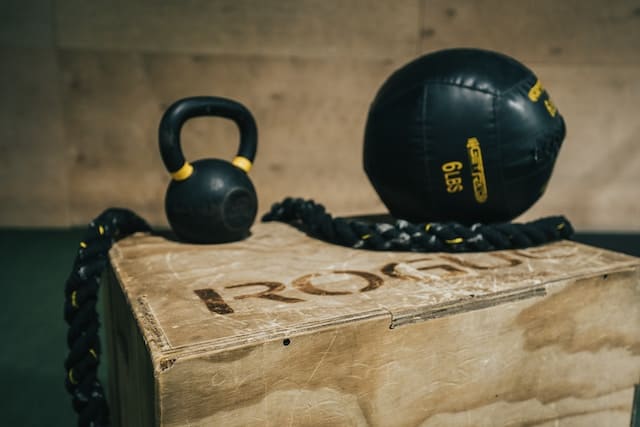Slam ball and kettlebell placed on a plyometric box, showcasing essential equipment for explosive training.
