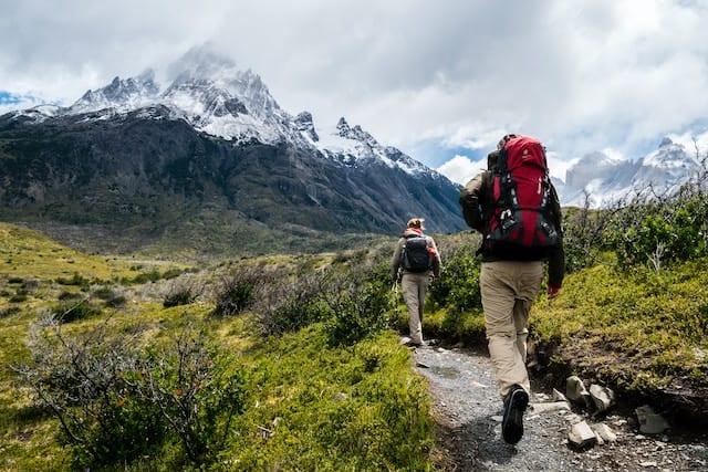 Man and woman hiking together through a picturesque mountain range, exemplifying the thrill of Outdoor Fitness Adventures