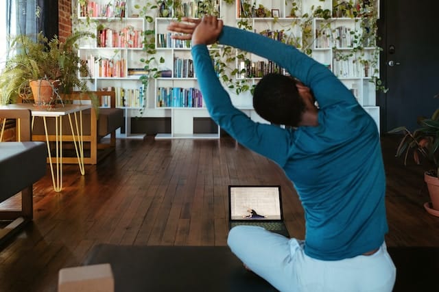Individual actively participating in a digital fitness class through their laptop, highlighting the role of Tech for Fitness Triumphs